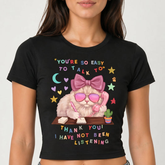 Black t-shirt with a graphic design of a cat wearing sunglasses and a bow, text, and a white background.