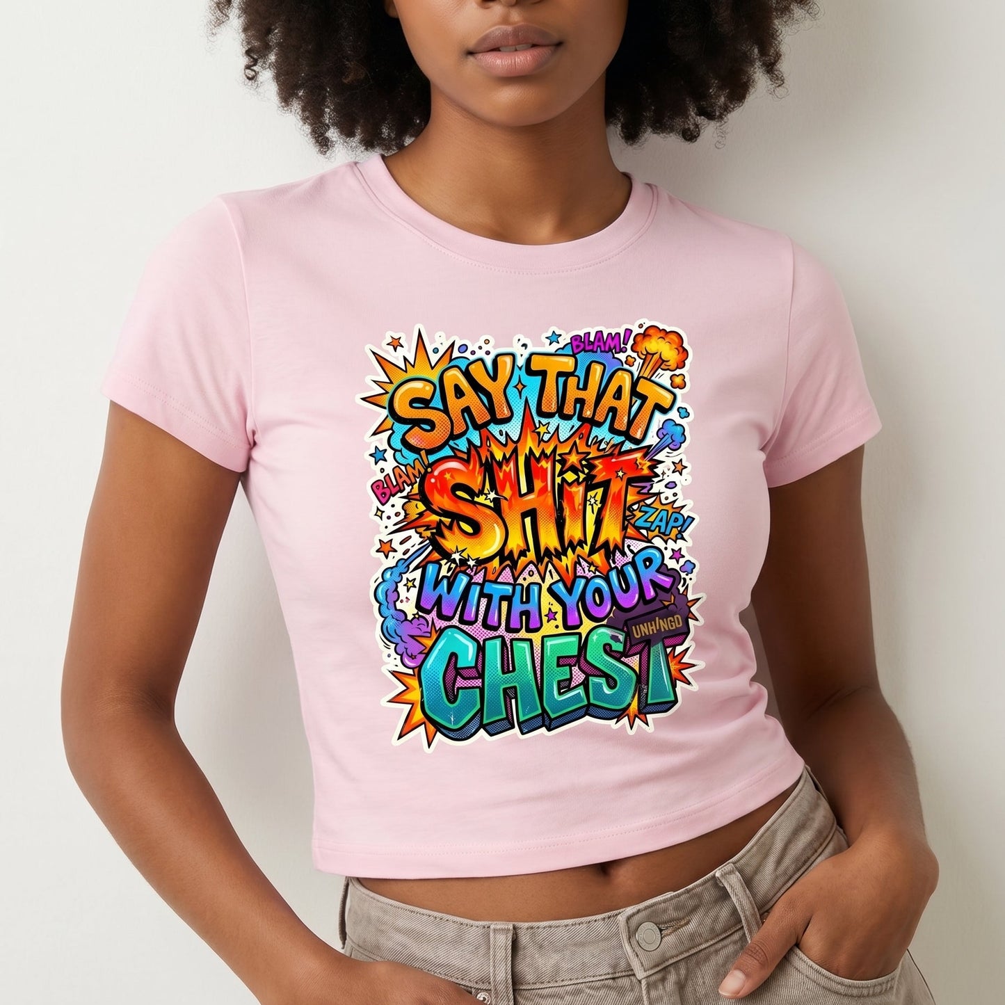 Person wearing a pink t-shirt with colorful text design on a plain background